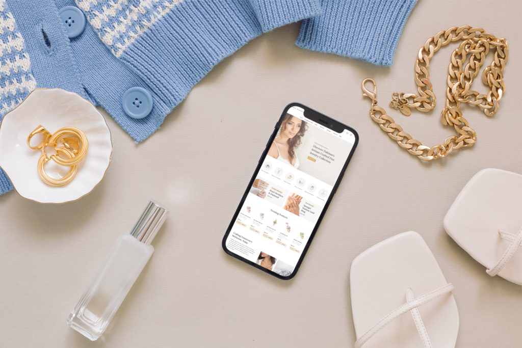 Smartphone displaying the Dakinaa jewelry website homepage, surrounded by jewelry and accessories